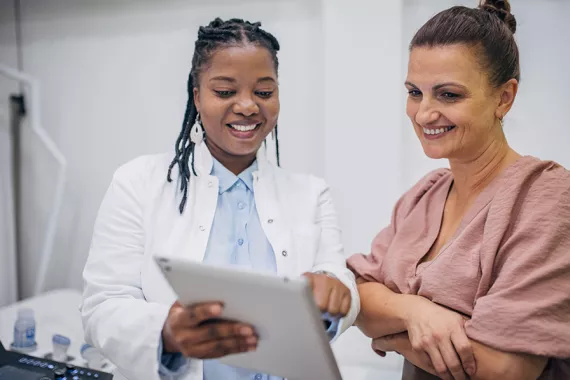 A doctor and patient discussing medical results on a tablet A doctor and patient discussing medical results on a tablet