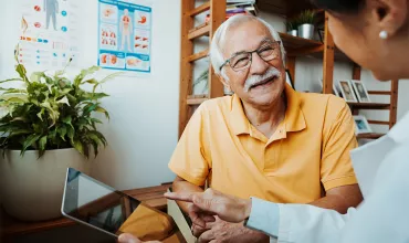 A healthcare professional and senior patient in a conversation using a tablet A healthcare professional and senior patient in a conversation using a tablet