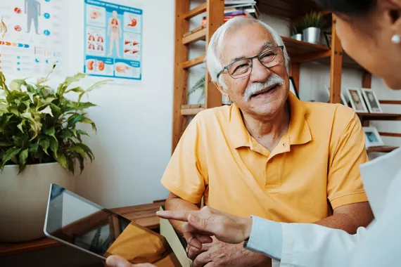 A healthcare professional and senior patient in a conversation using a tablet A healthcare professional and senior patient in a conversation using a tablet