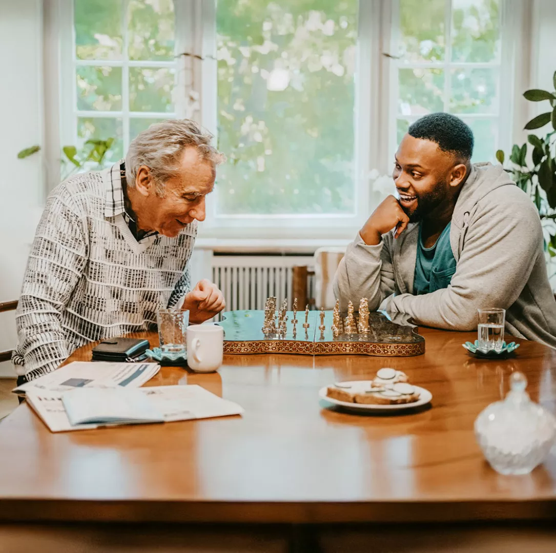 Young and senior men laughing while playing chess